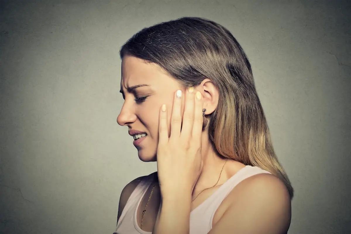 Side profile shot of someone holding their hand next to their ear in pain