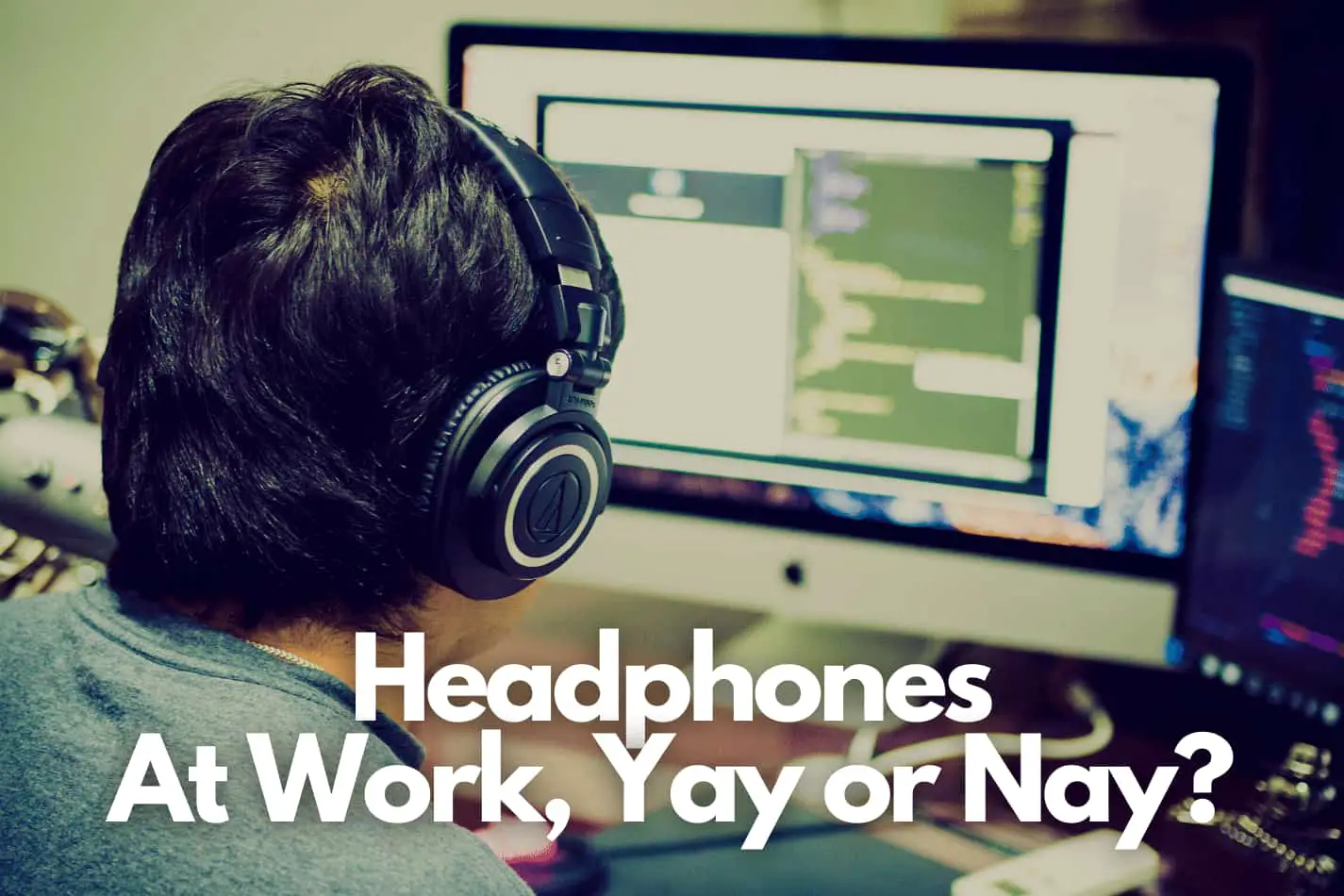 Man wearing headphones while working at a mac desktop